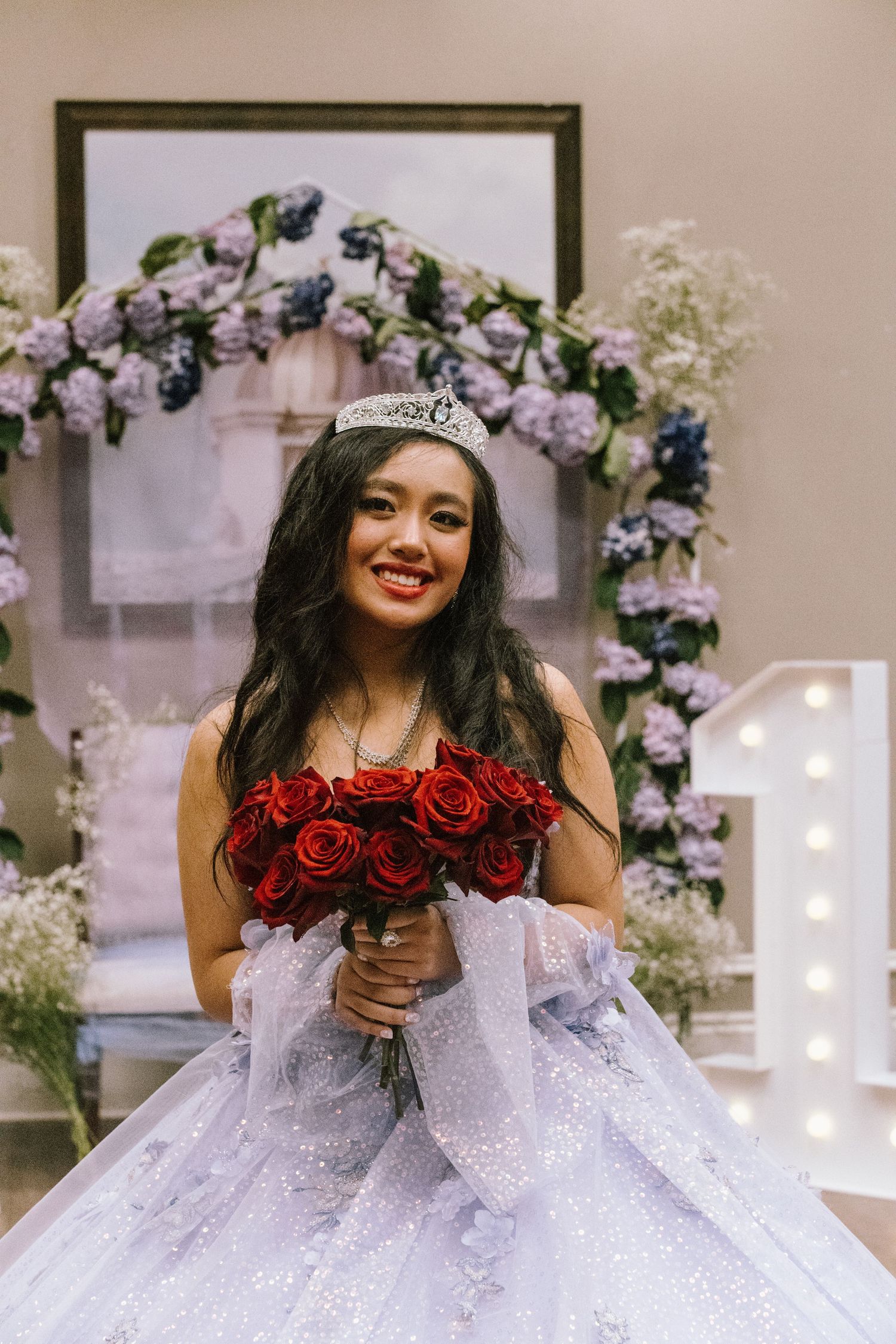 A celebration portrait featuring a bouquet of red roses and a lavender tulle gown.