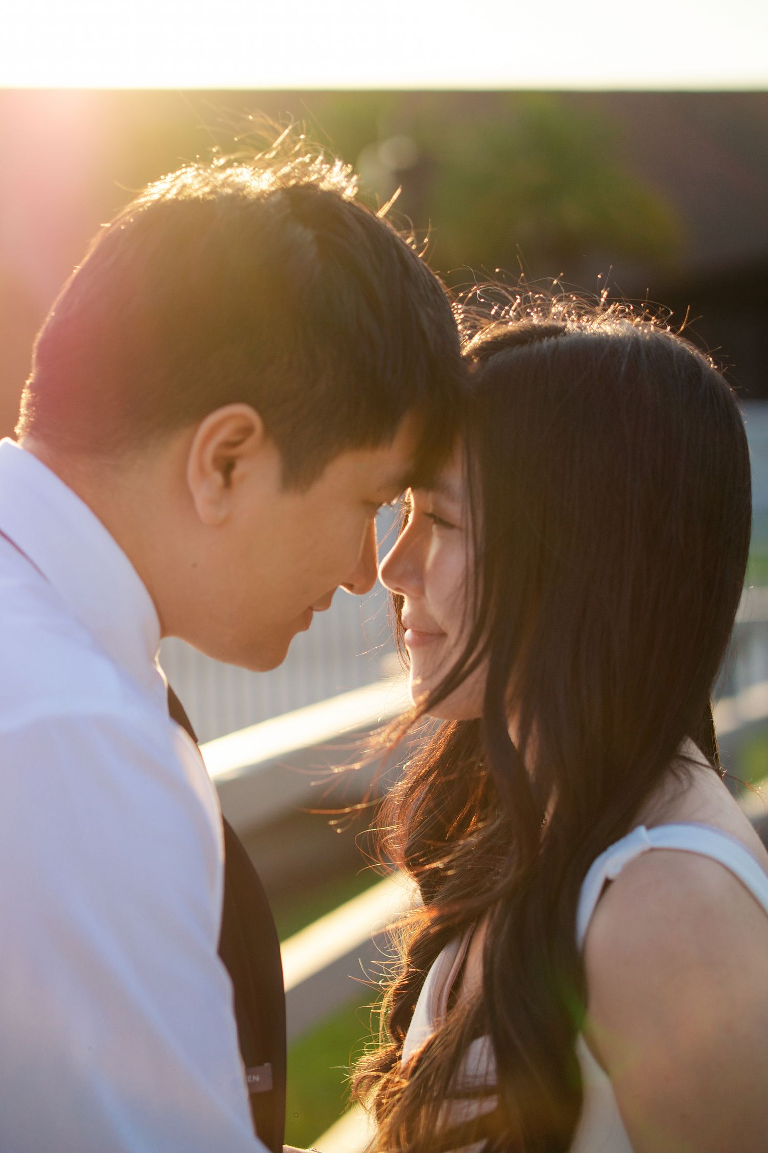 A romantic couple shares an intimate moment at sunset with golden light illuminating their silhouettes.