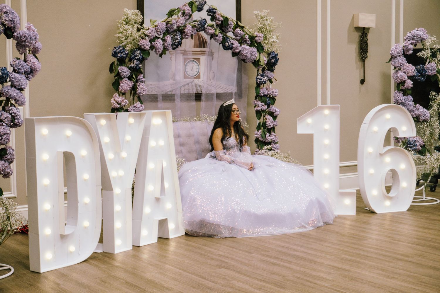 Quinceañera celebration setup with illuminated letters and floral arch decorations.