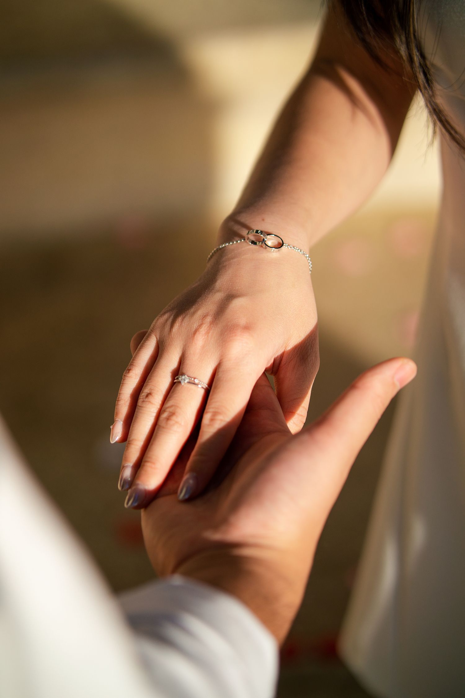 Close-up of hands showing engagement ring and wedding band in soft natural lighting.