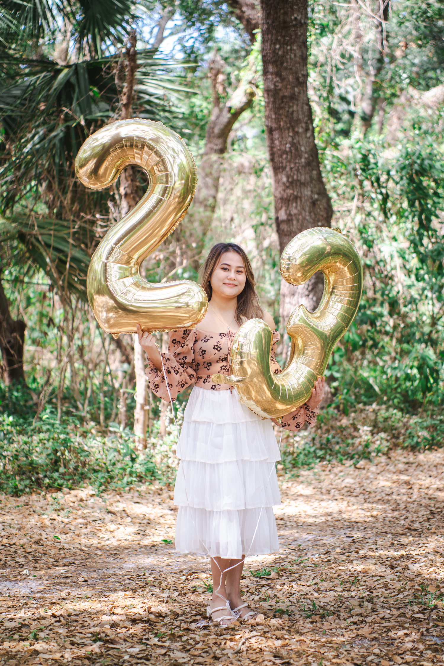 Gold number balloons spelling '20' against a lush forest background.