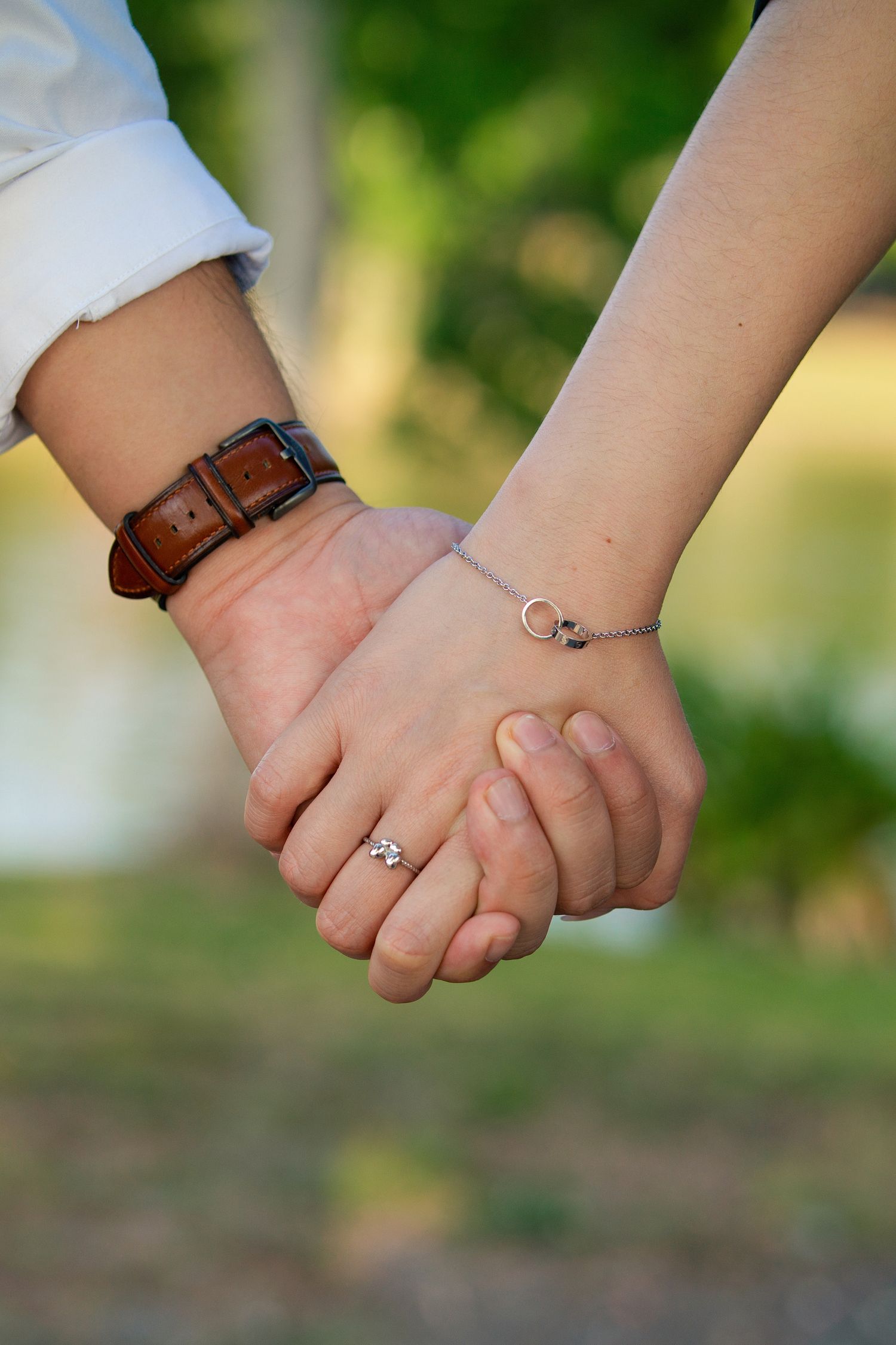A sequence of photos showing two people holding hands with bracelets and rings visible against a blurred green background.