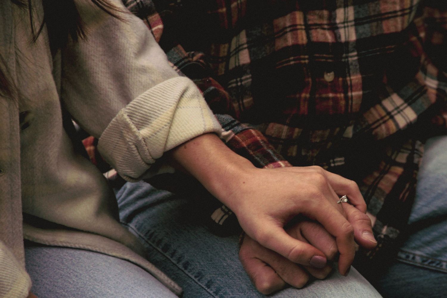 Close-up of two people holding hands while wearing casual clothing of denim jeans and plaid flannel.