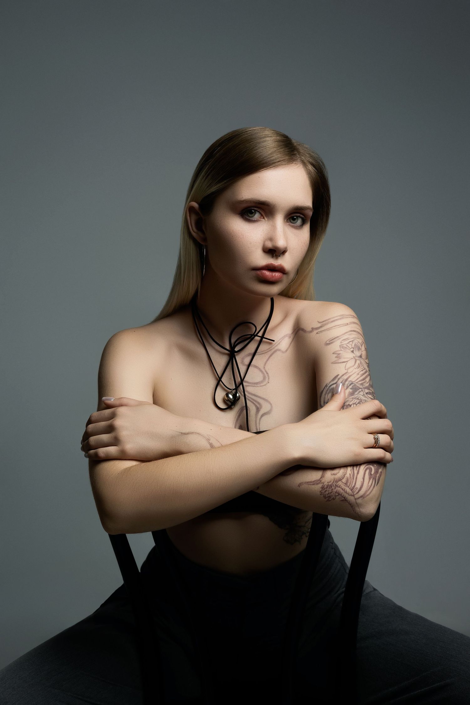 Artistic studio portrait featuring minimalist styling and delicate necklace detail.