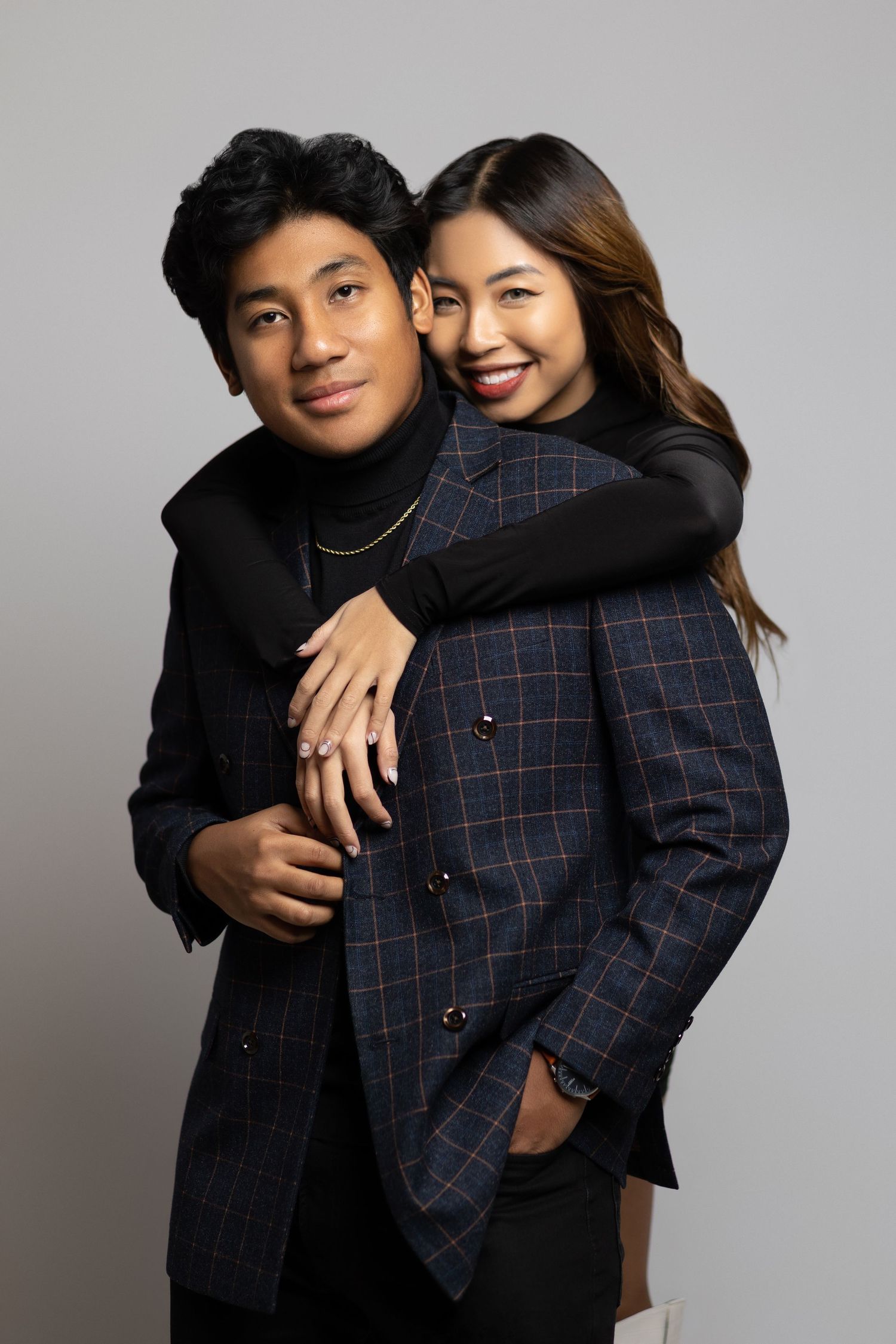 Studio portrait of couple embracing in stylish winter outfits.