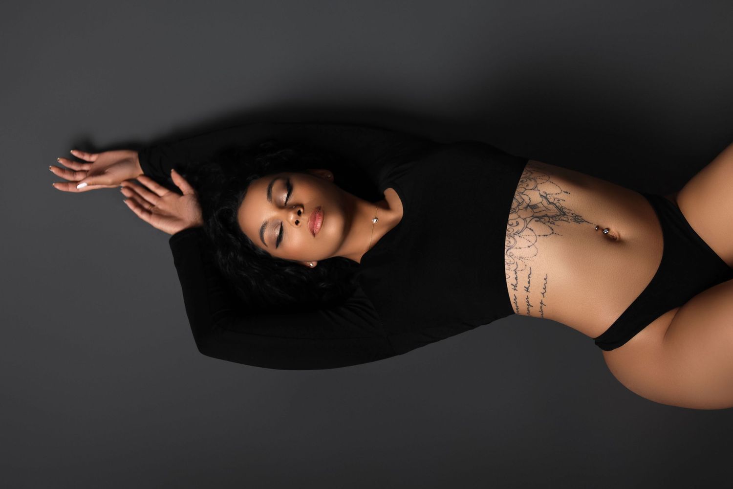 Overhead view of figure in black clothing against dark background.