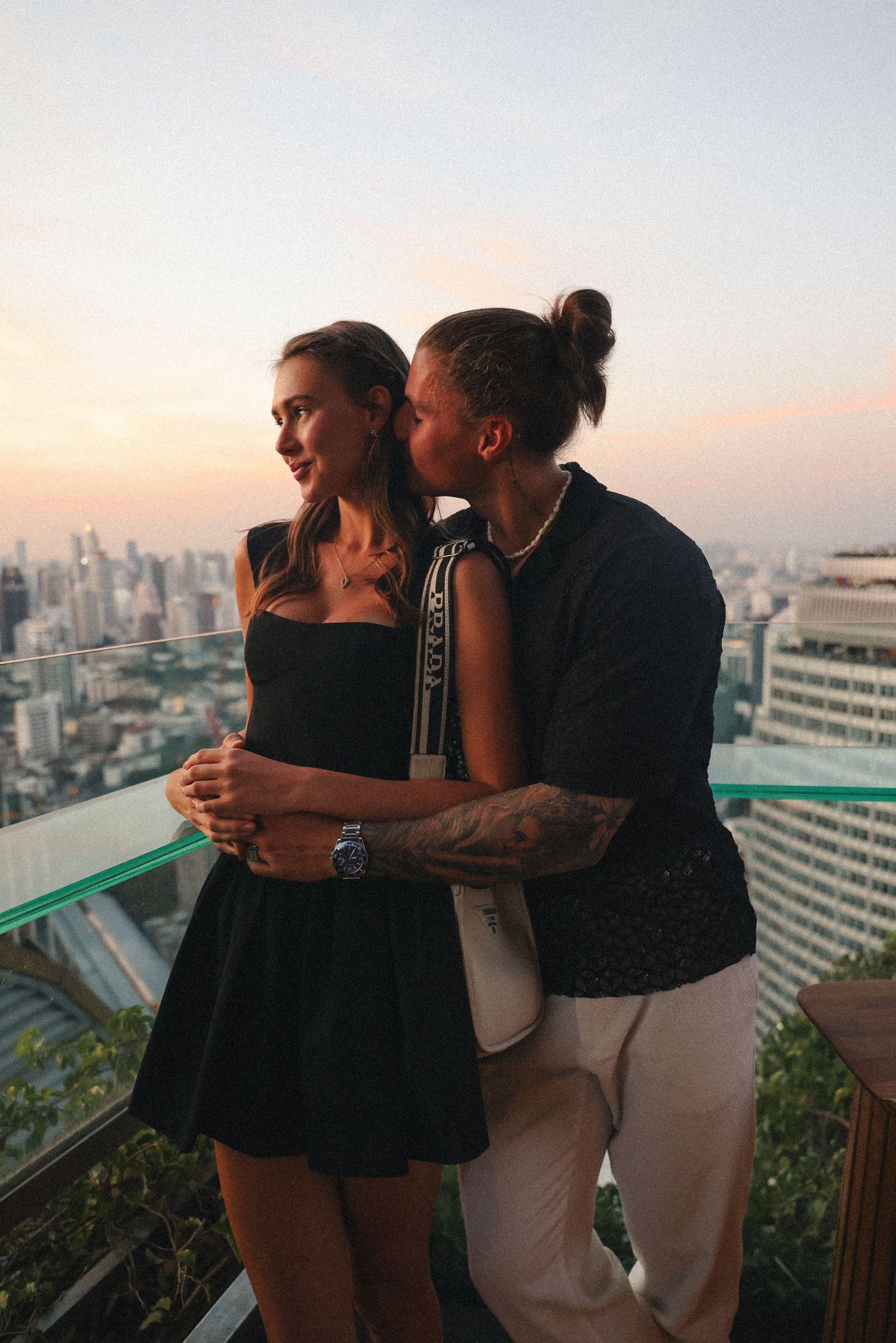 Romantic rooftop moment overlooking city skyline at sunset.