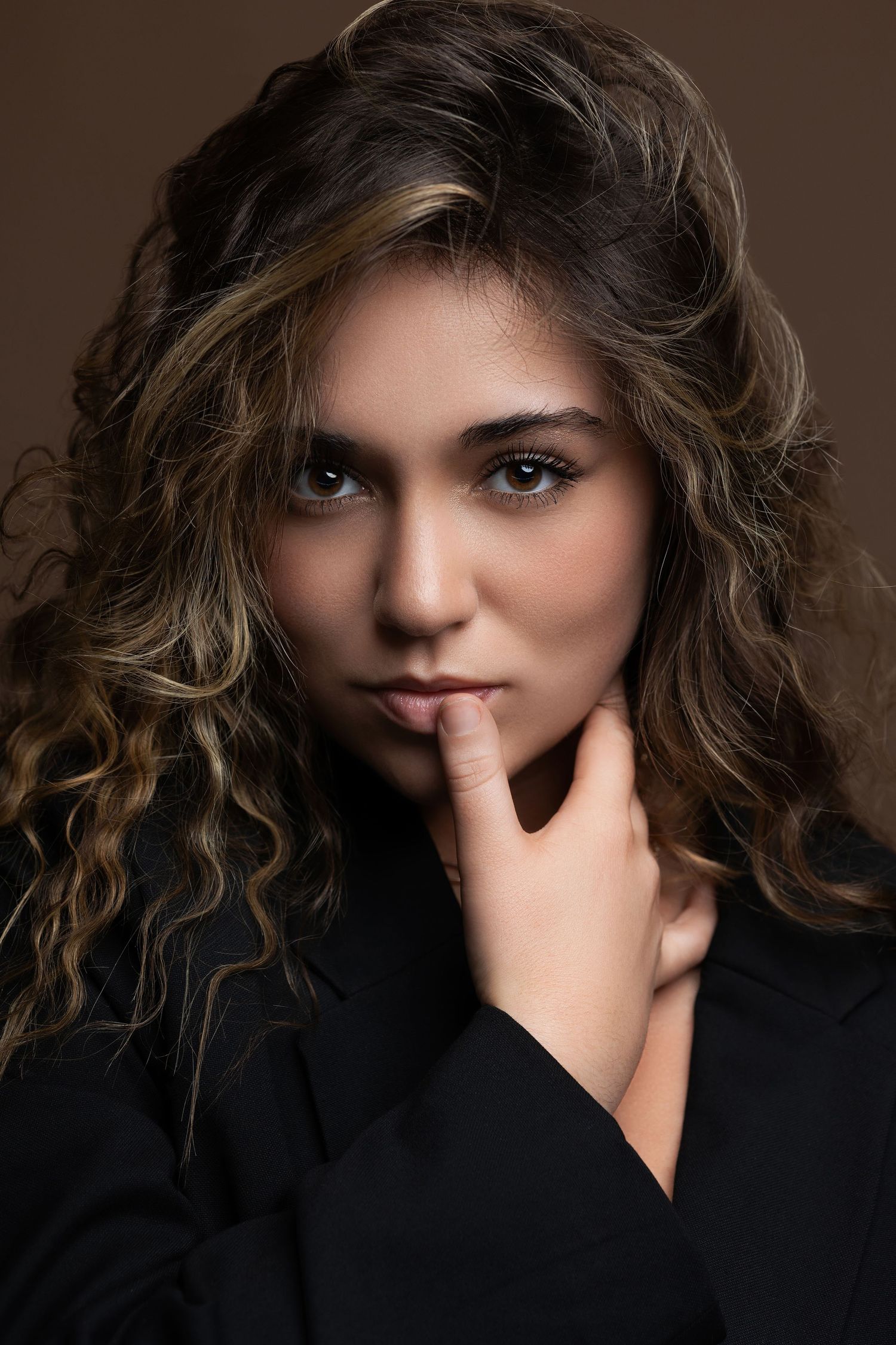 Studio portrait showcasing dramatic lighting and textured hair against a dark background.