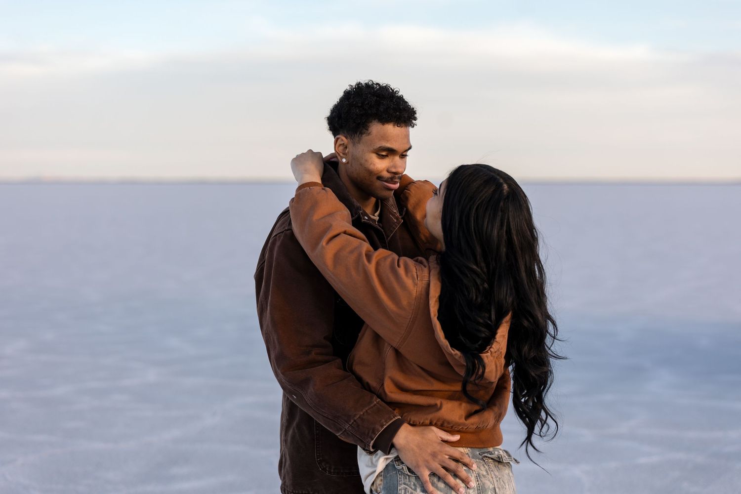 Romantic embrace captured against winter landscape backdrop.