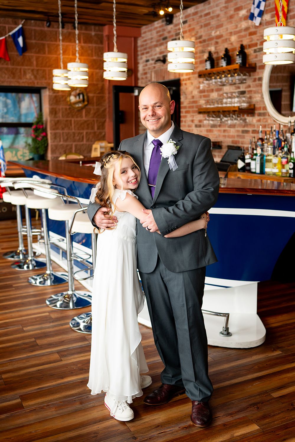 Wedding reception venue with exposed brick walls, pendant lights and navy blue bar seating.