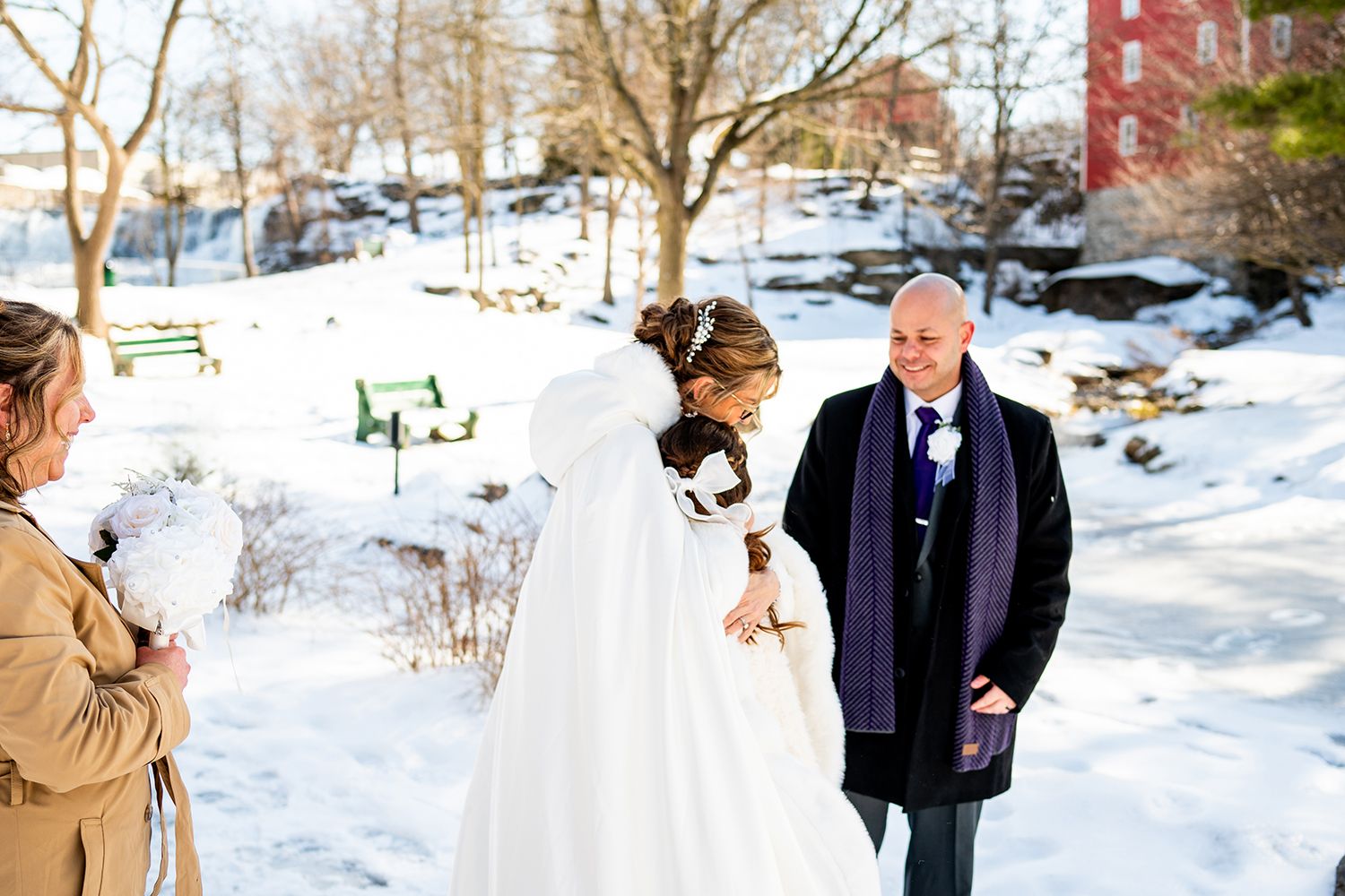 Winter wedding couple walks together through snowy landscape while sharing an intimate moment outdoors.