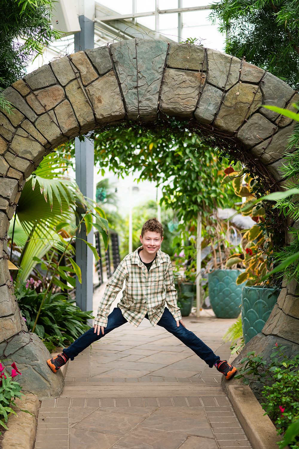 Stone archway in a lush garden pathway framing a joyful pose on the walkway.