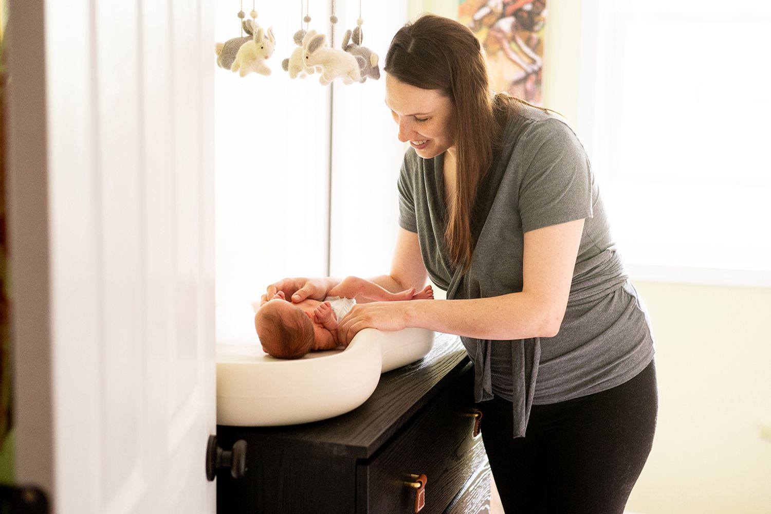 A chiropractor gently adjusts a patient lying on a treatment table in a bright, serene clinic room.