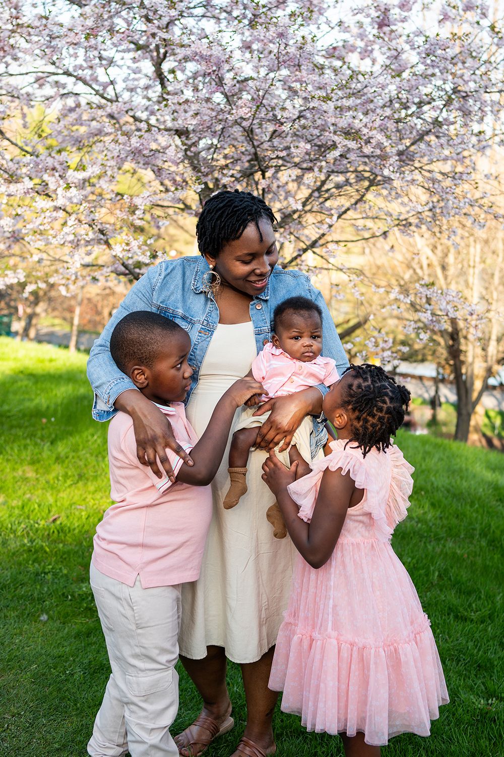 Children play and laugh together under blooming cherry blossom trees in springtime.