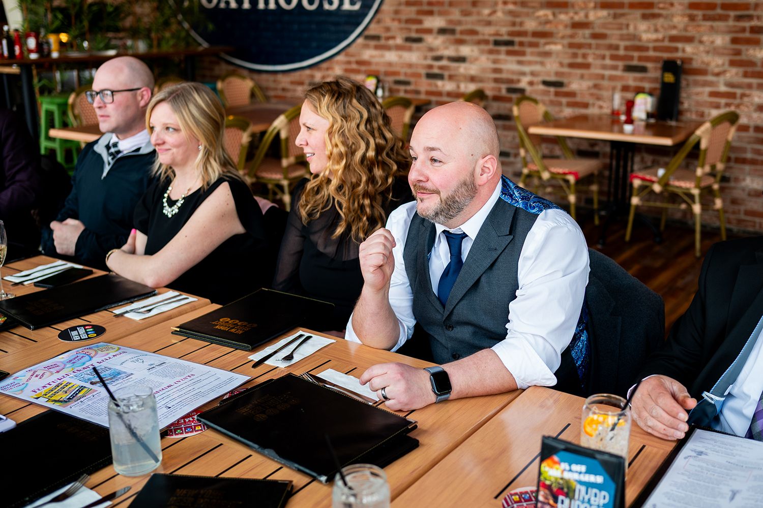 Wedding guests and wedding party seated at wooden tables during reception at rustic brick venue.