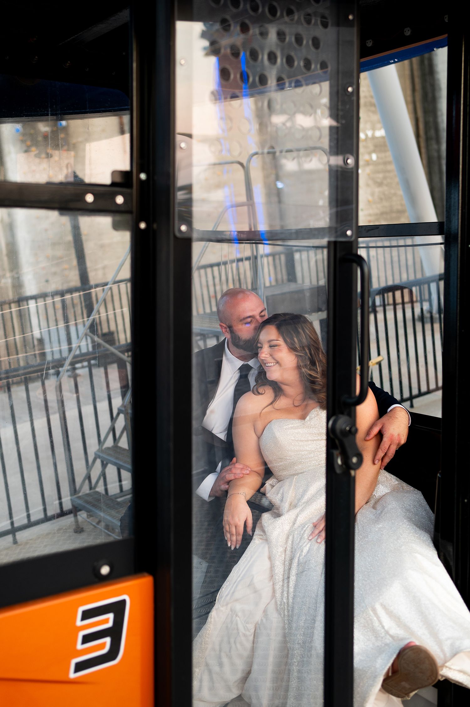 A couple shares a romantic moment inside an orange ski gondola lift cabin.