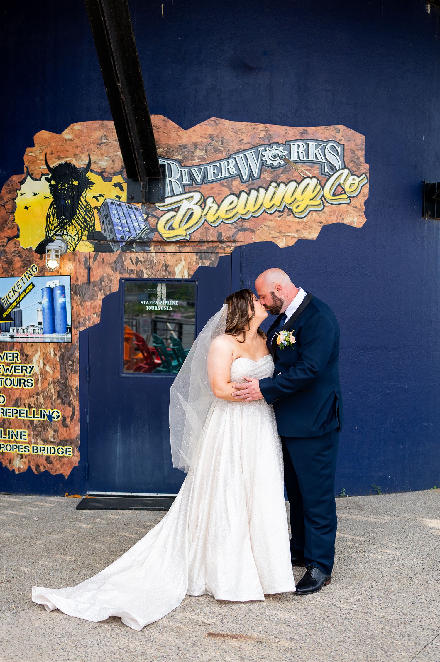 A couple shares a romantic kiss in front of a colorful graffiti wall during their wedding photo session.