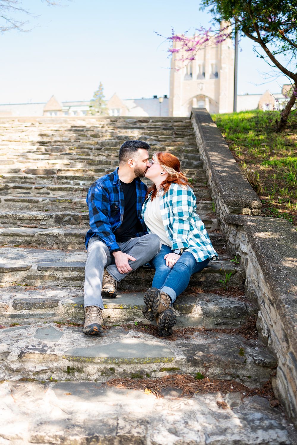 Two people in casual attire sit and relax together on old stone steps during a sunny day.