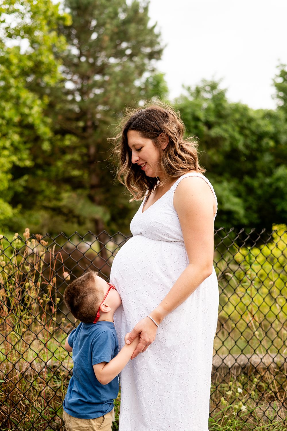 A series of tender moments between a woman in a white dress and a child in blue against a green outdoor backdrop.