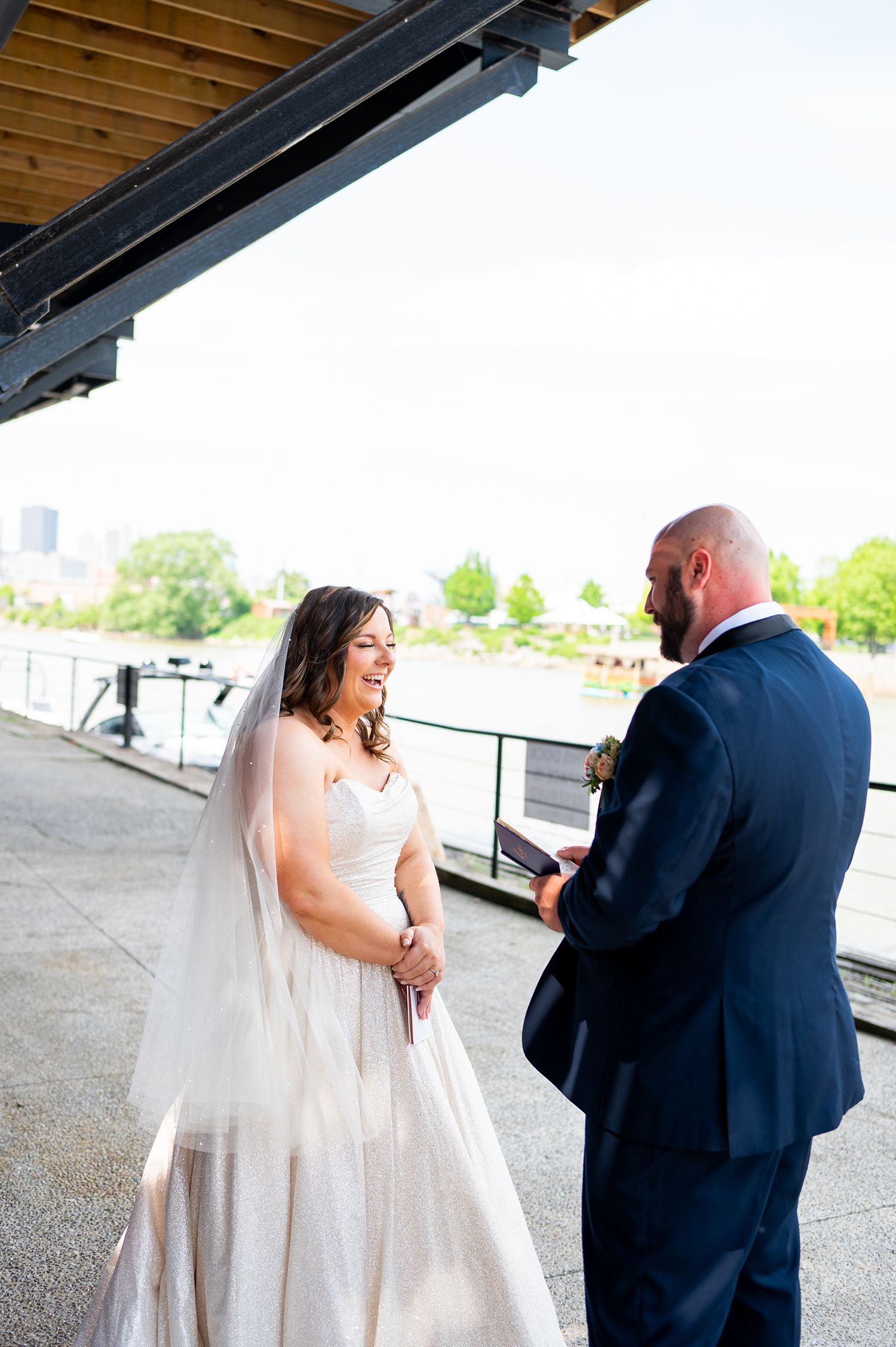 First look moment captured between couple on an outdoor deck with city skyline in background.