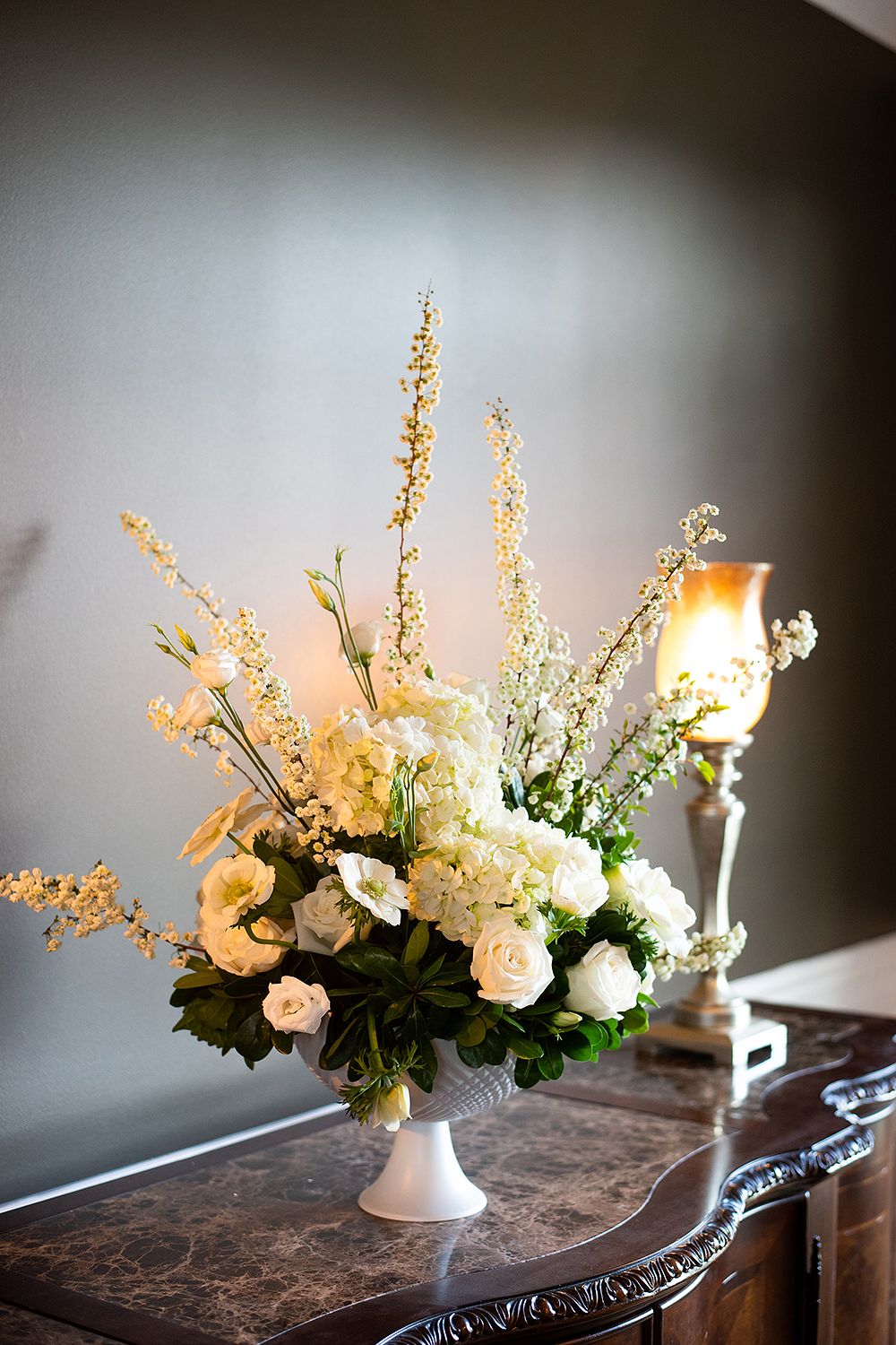 A time-lapse sequence of white and cream floral arrangements with delicate blooms in a ceramic vase on a dark wooden surface.