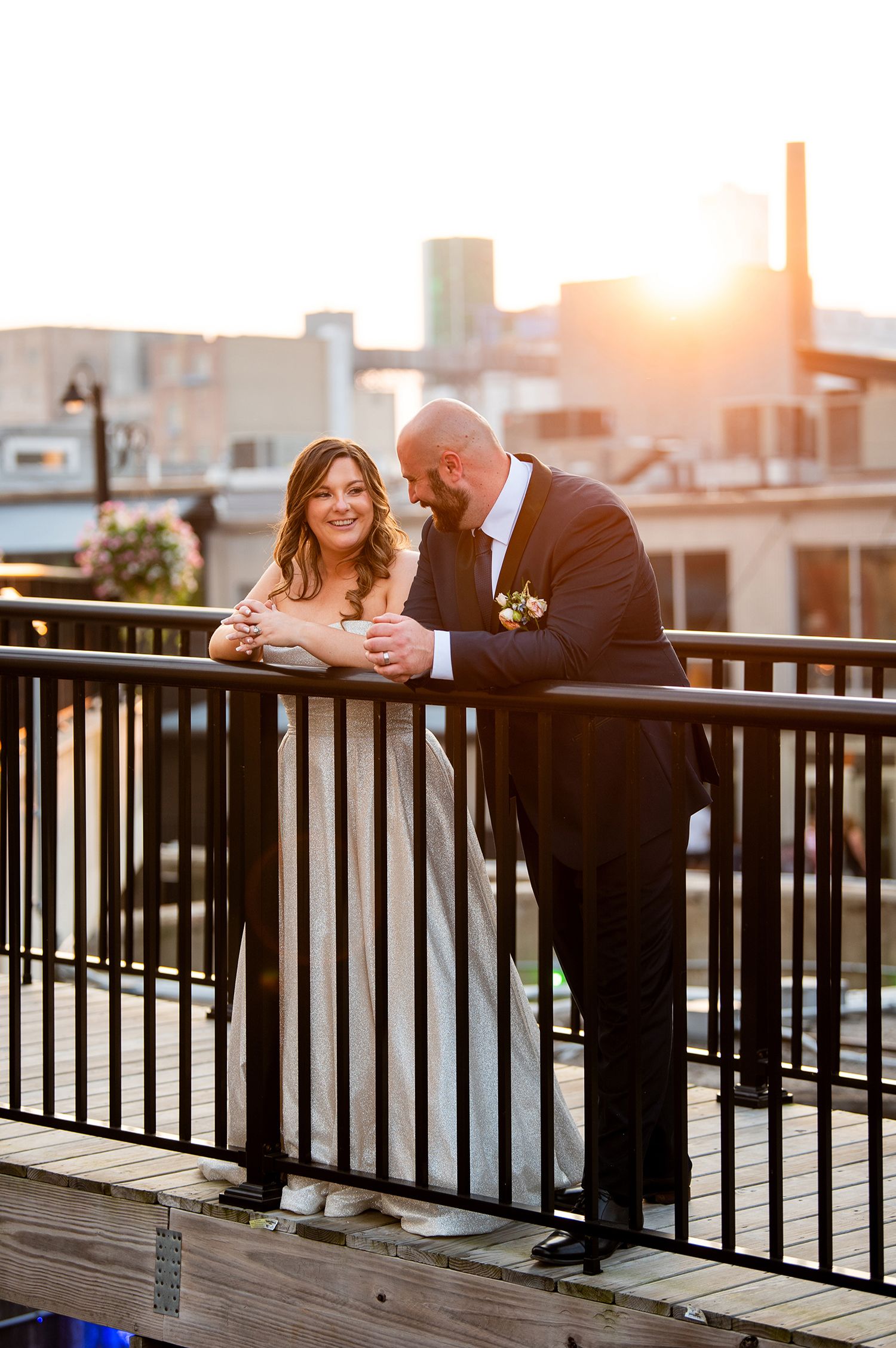 Romantic sunset wedding photos on a deck with city buildings in the background.