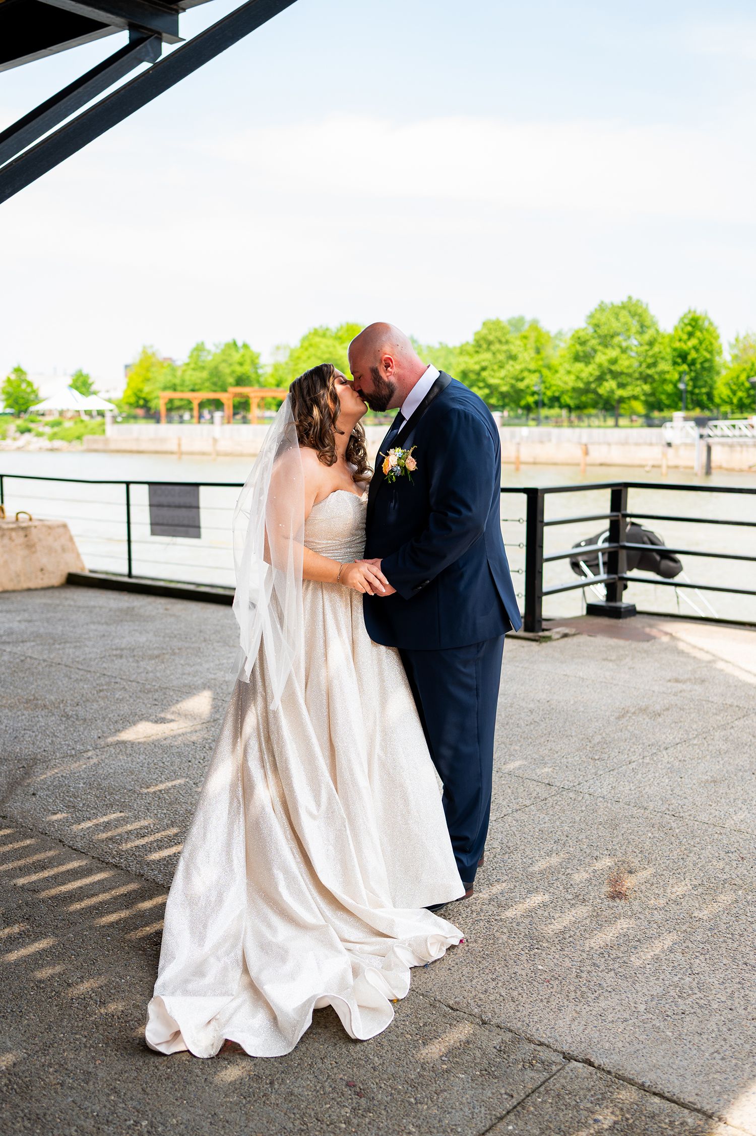 A couple shares a romantic moment on their wedding day on an outdoor terrace in formal attire.