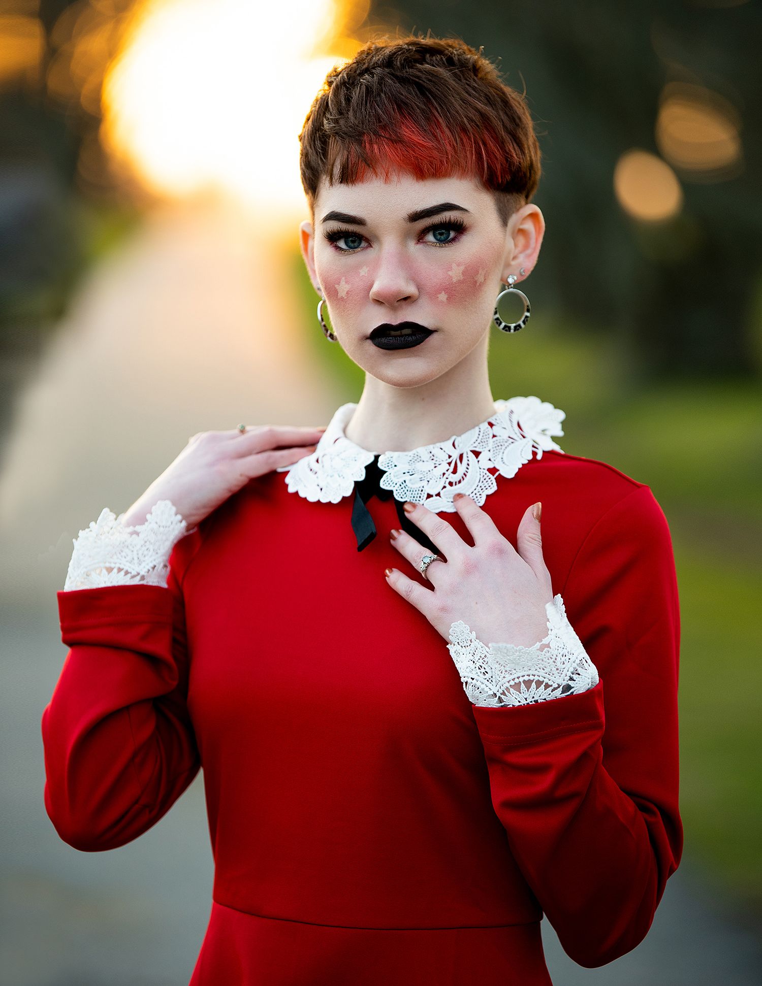 Vintage-inspired portrait featuring a red dress with white lace collar and cuffs against a warm bokeh background.
