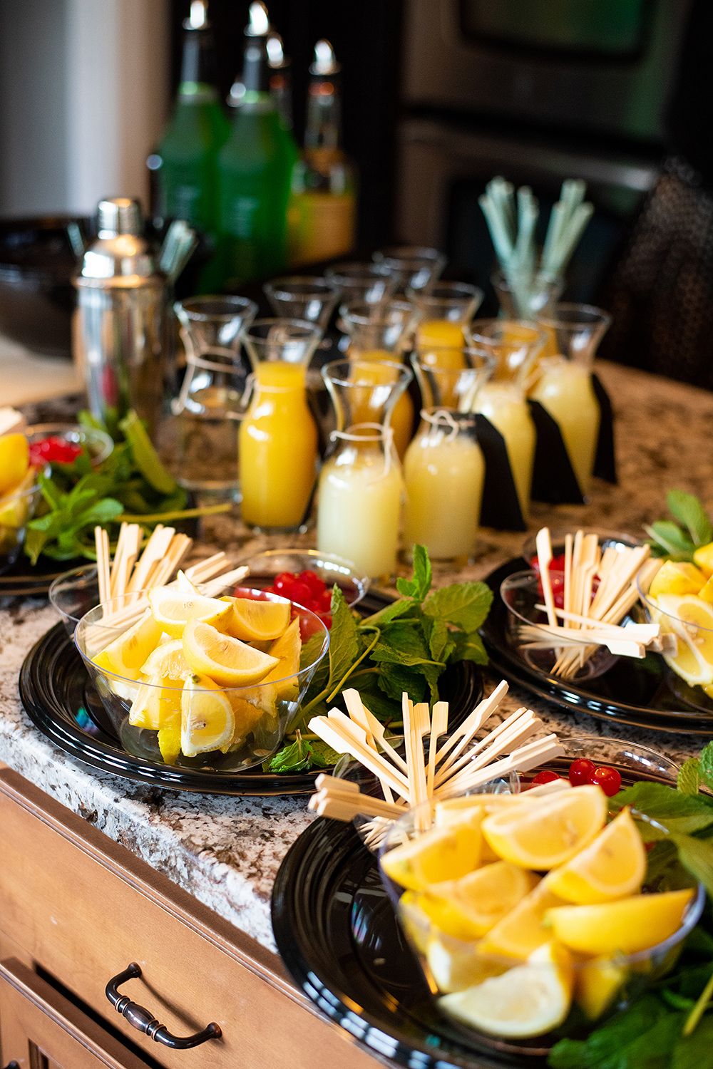 Fresh appetizer display with citrus wedges, garnishes and chilled beverages in mason jars on an ice-filled tray.