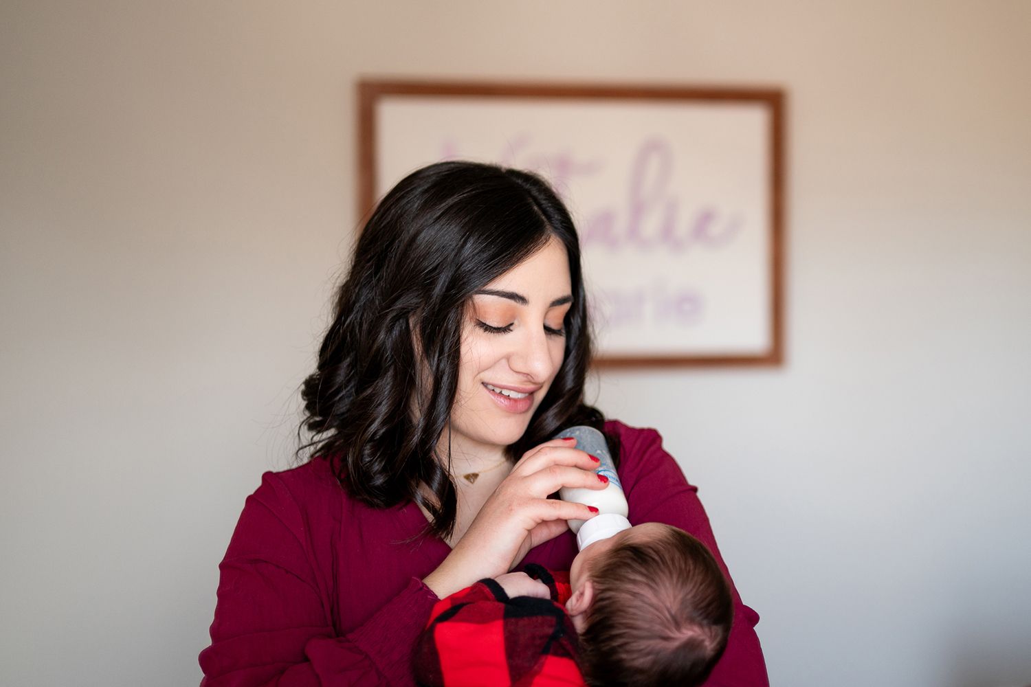 A tender moment between a person in a maroon sweater and a baby in a soft, naturally lit room.