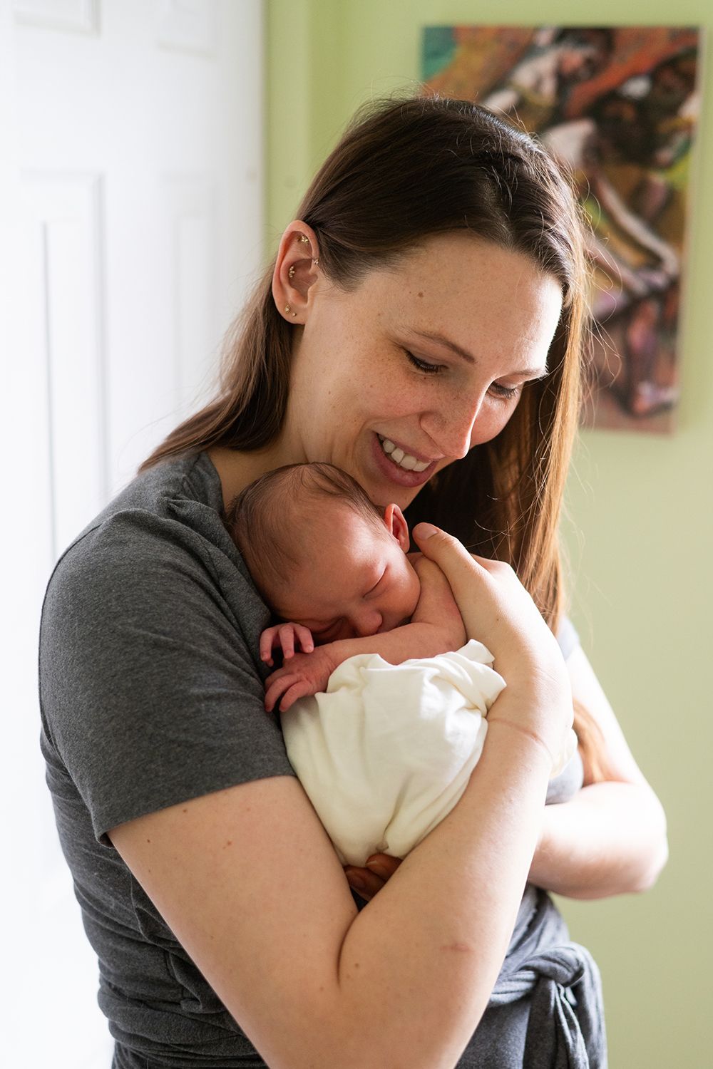 An intimate moment of bonding while holding a sleeping newborn baby in a grey t-shirt.