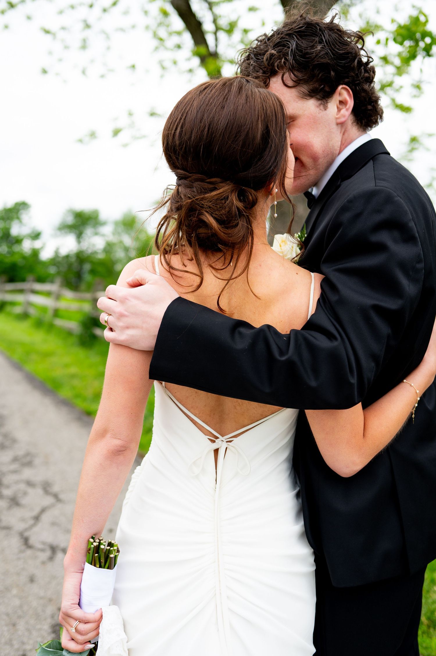A series of romantic wedding photos showing a couple in formal attire embracing outdoors on a path with greenery.
