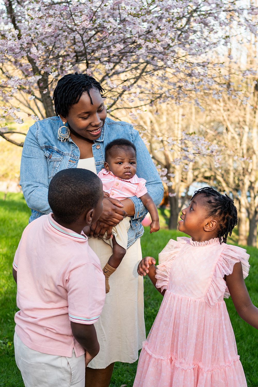 Family enjoying playful moments together in a spring garden with blooming trees in the background.