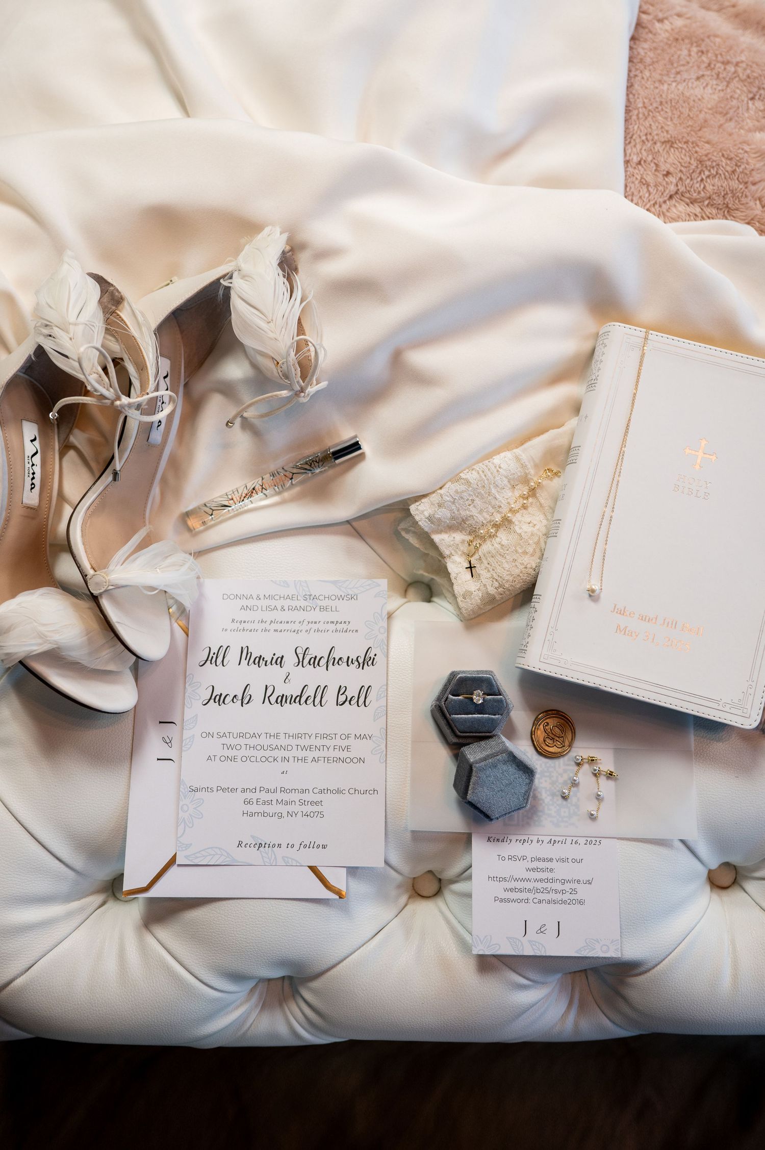 Elegant wedding invitation suite with white stationery, wax seals, and silk ribbon laid out on soft fabric.