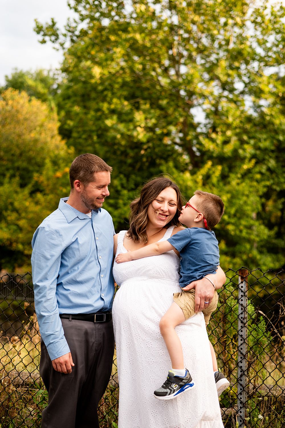 A loving family moment outdoors in a lush green park setting on a sunny autumn day.