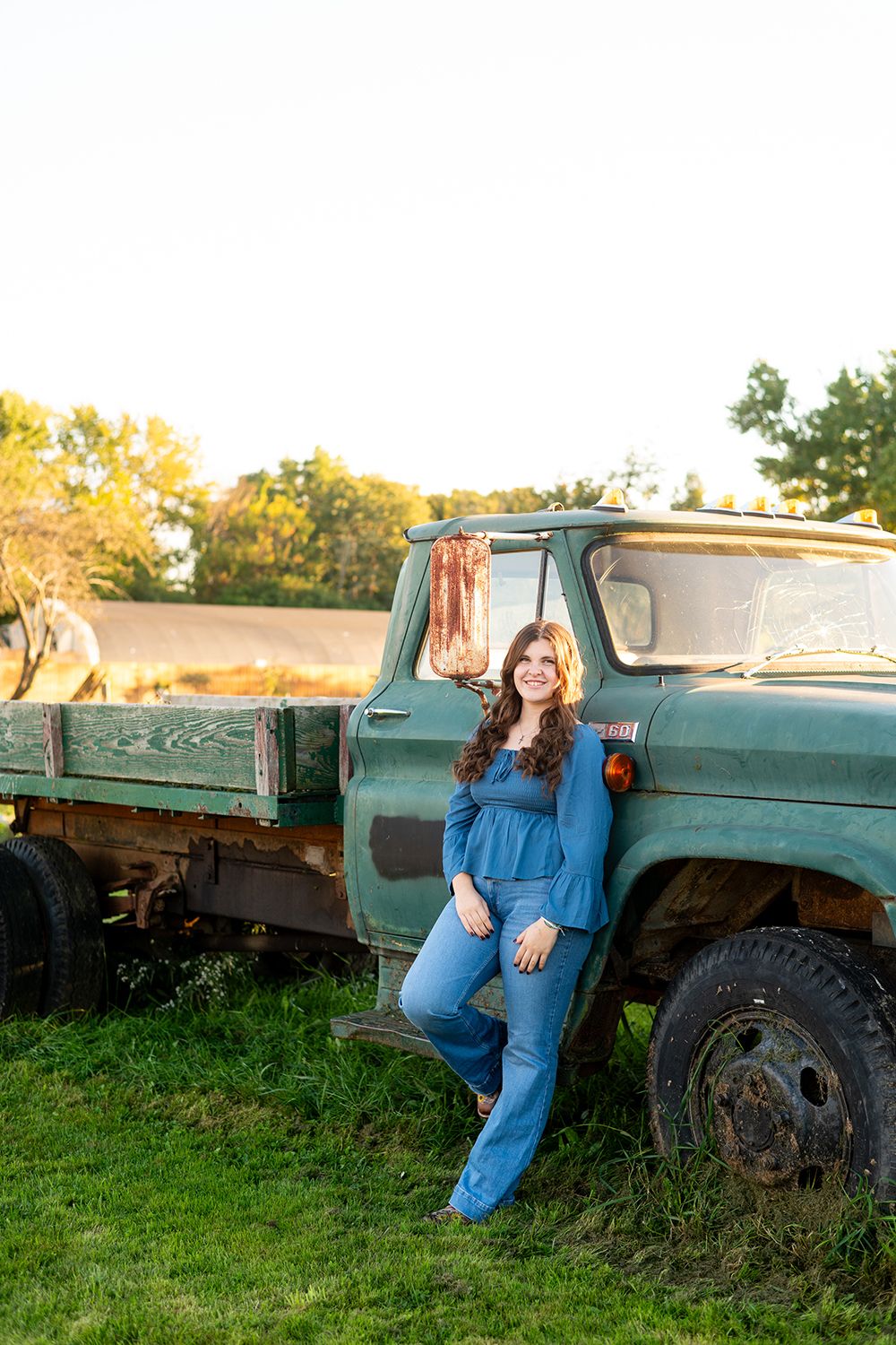 High school senior photo session featuring vintage green truck in golden sunset light with casual country styling.