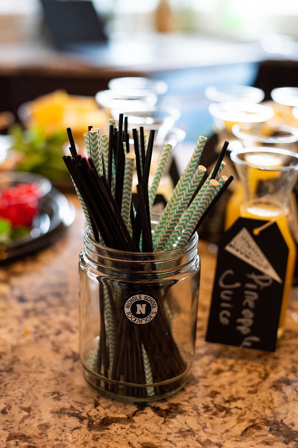 Black and white striped paper straws arranged in glass jars on a granite countertop surface.