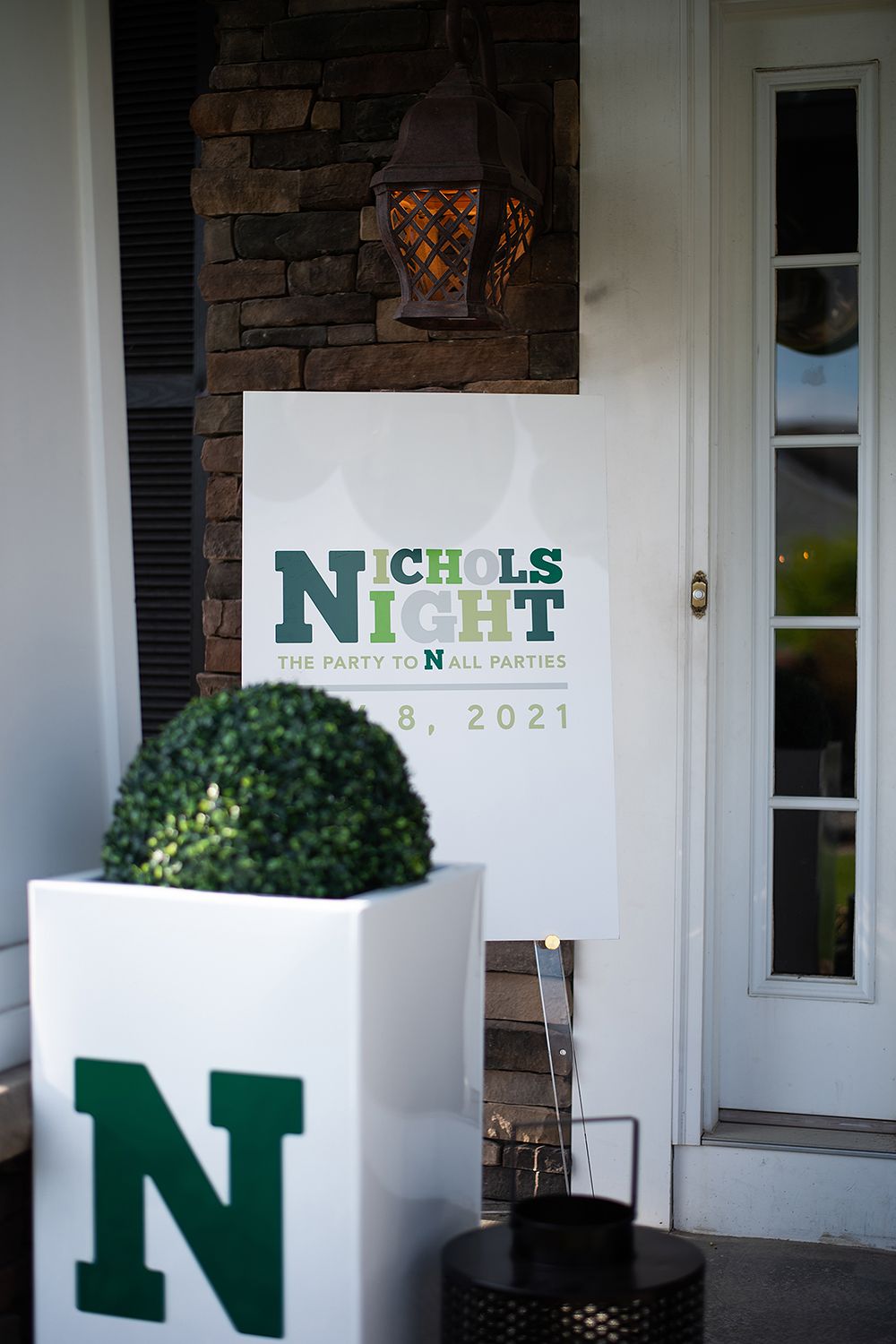 Decorative front porch display with white planter and green 'Nichols Night' signage for 2021 event.