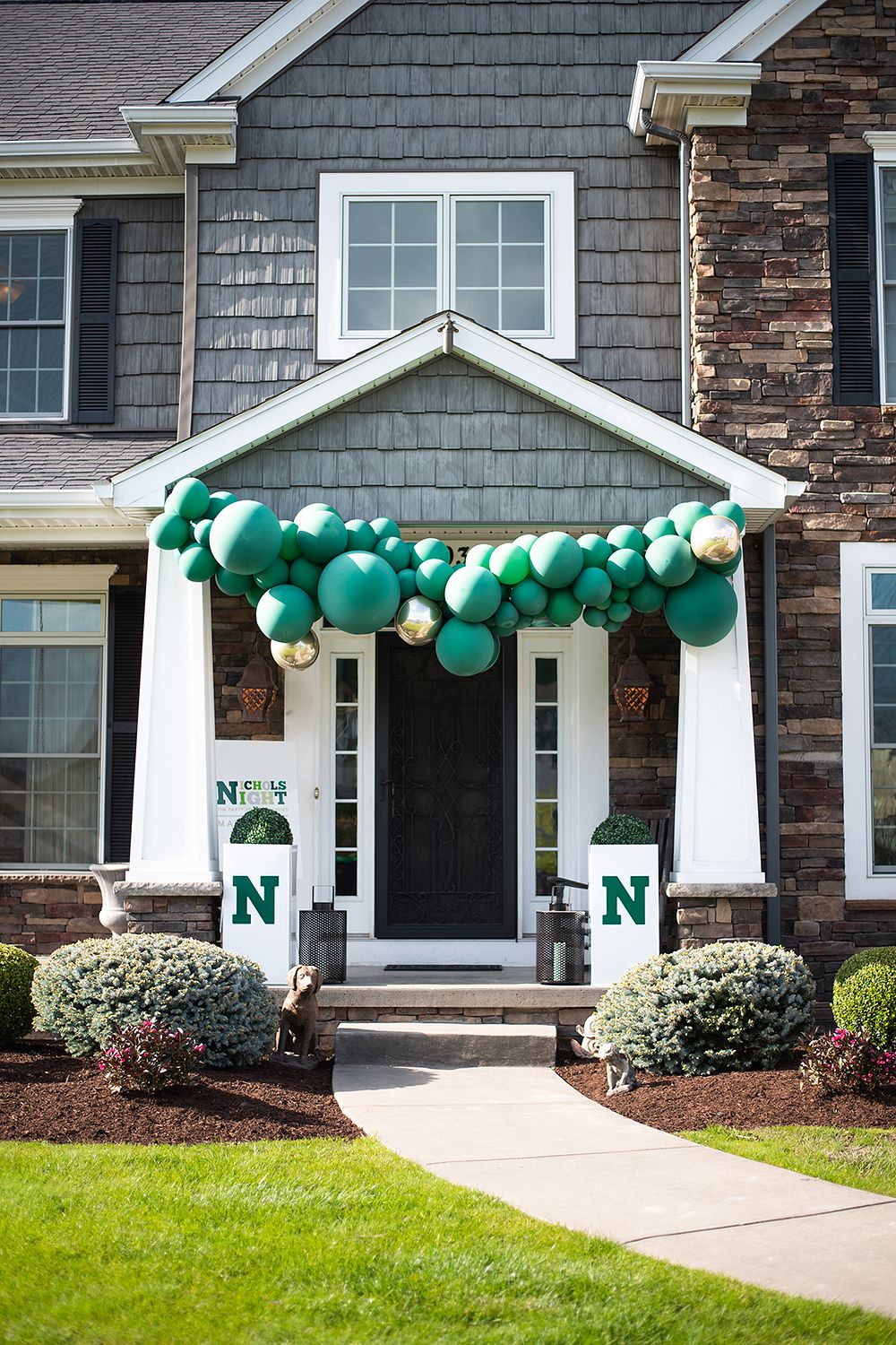 Gray townhouse entrance decorated with festive green balloons along the roofline and a letter N by the front door.