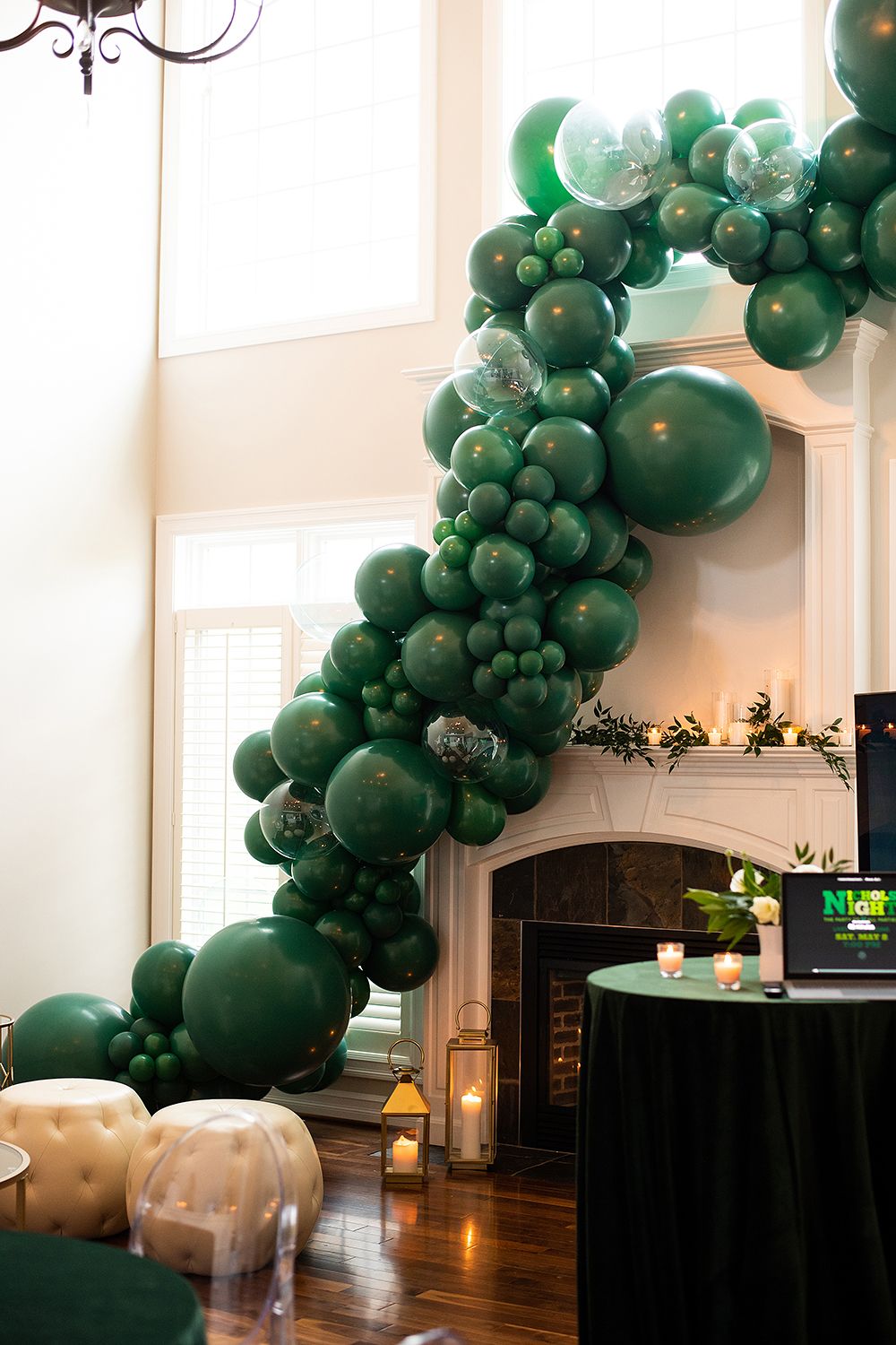 Emerald green balloon arch installation curves elegantly along white walls in an indoor event space.