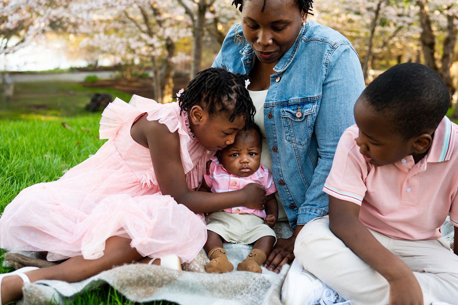 Family enjoying a picnic together on a blanket in a green park during springtime.