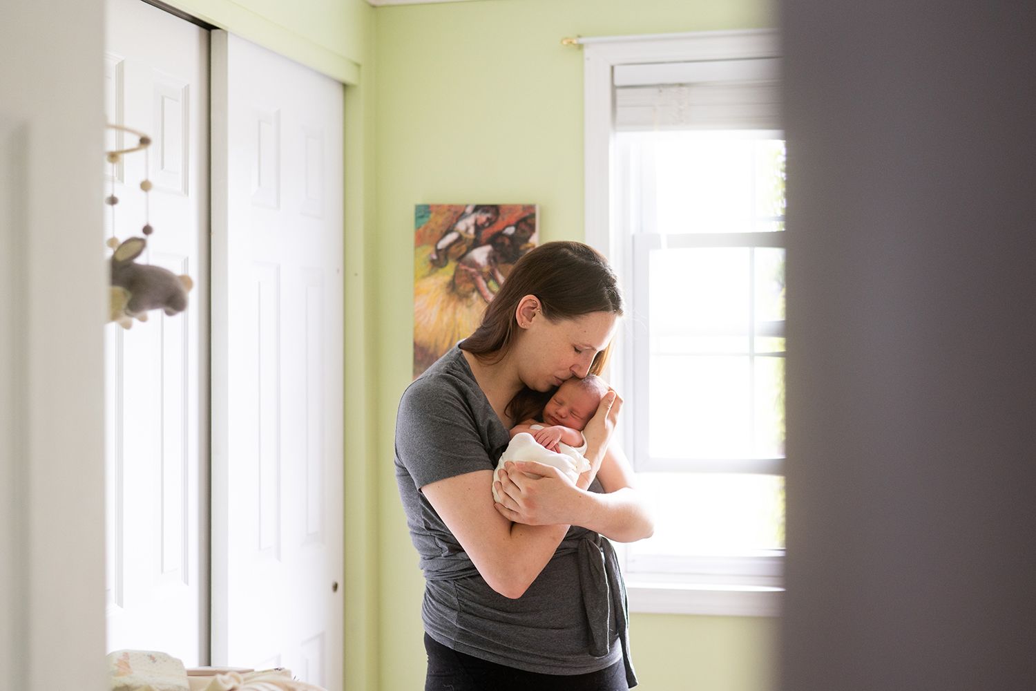 A peaceful moment embracing a newborn baby in a bright sunlit room with white walls.