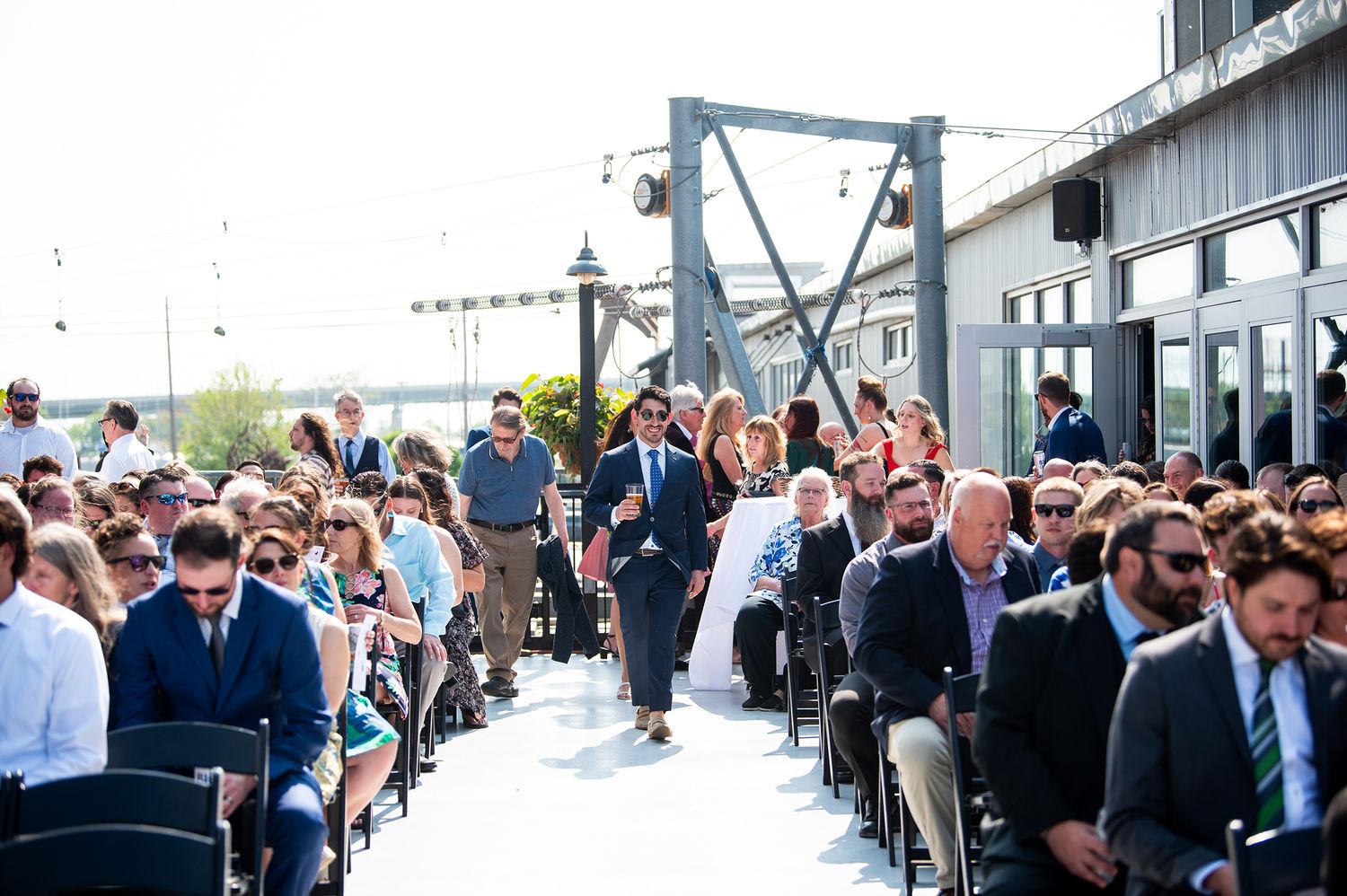 Wedding guests mingle and socialize during an outdoor cocktail reception at a rustic venue.