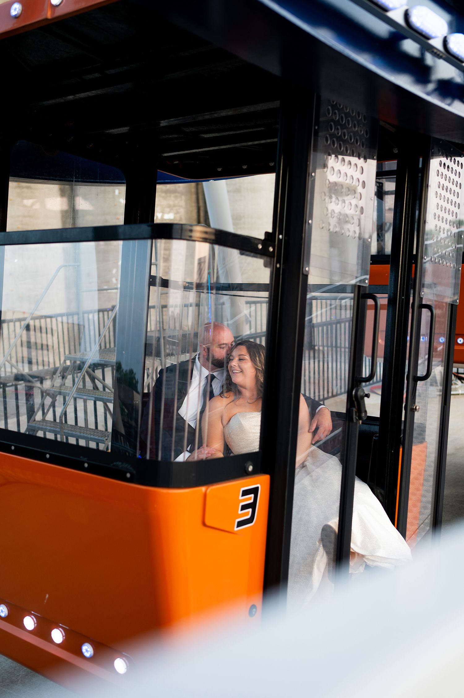 Wedding couple embraces inside a bright orange cable car gondola against a scenic backdrop.