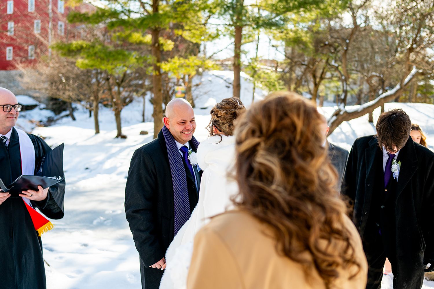 Wedding guests gather in a snowy winter landscape as they prepare for an outdoor ceremony.