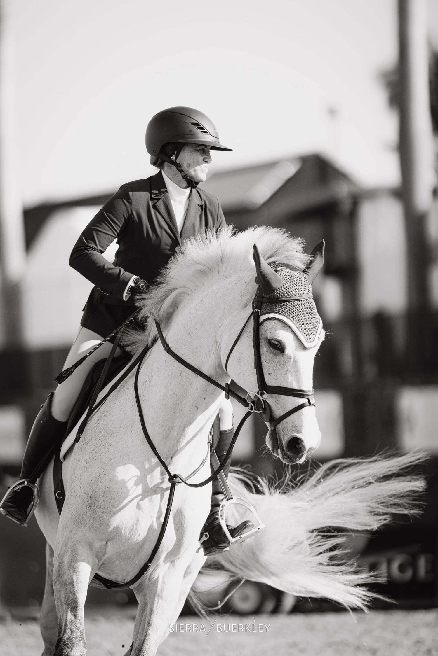 Black and white photo of a white horse and rider in elegant equestrian competition attire.