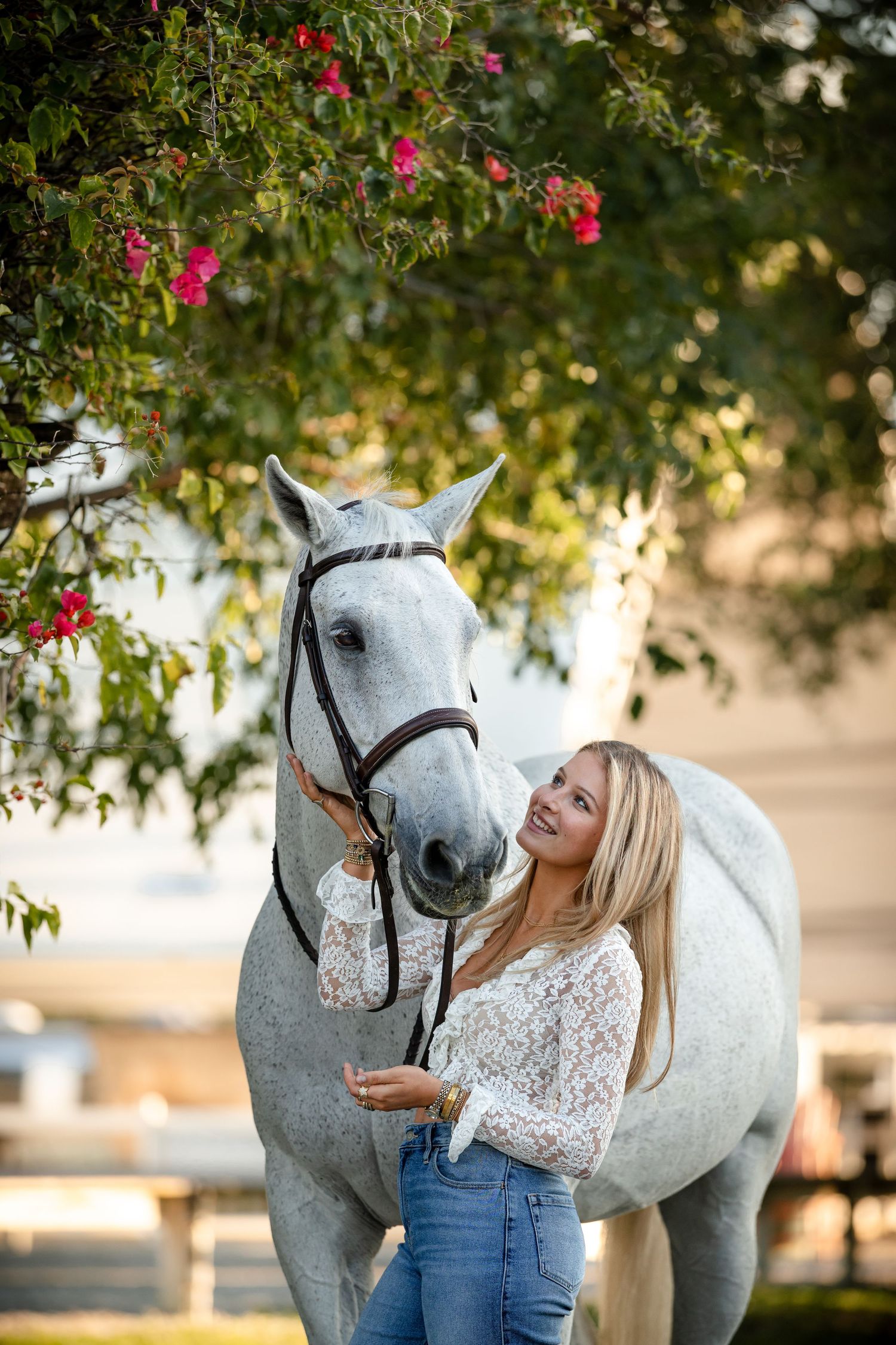 A series of photos showing a white horse and rider in casual attire posing together under flowering trees at sunset.