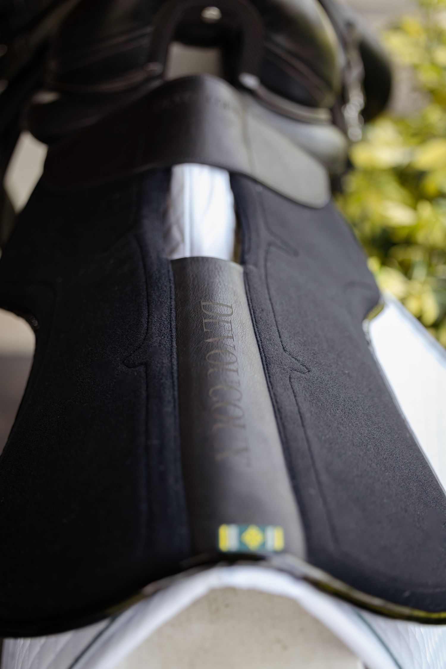 Close-up of black leather equestrian equipment with embossed branding.