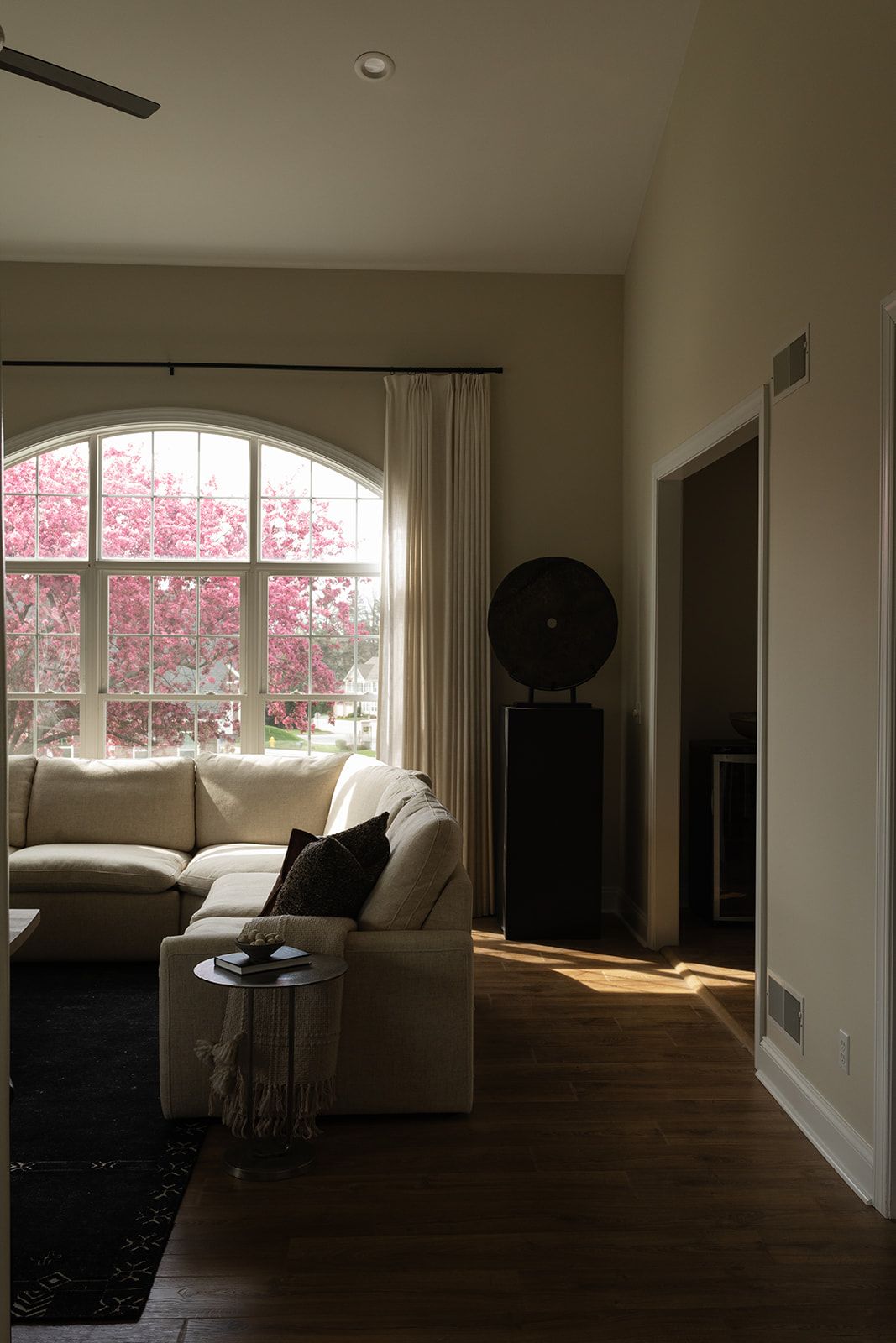 Spacious living room interior with hardwood floors and large arched windows letting in natural light.