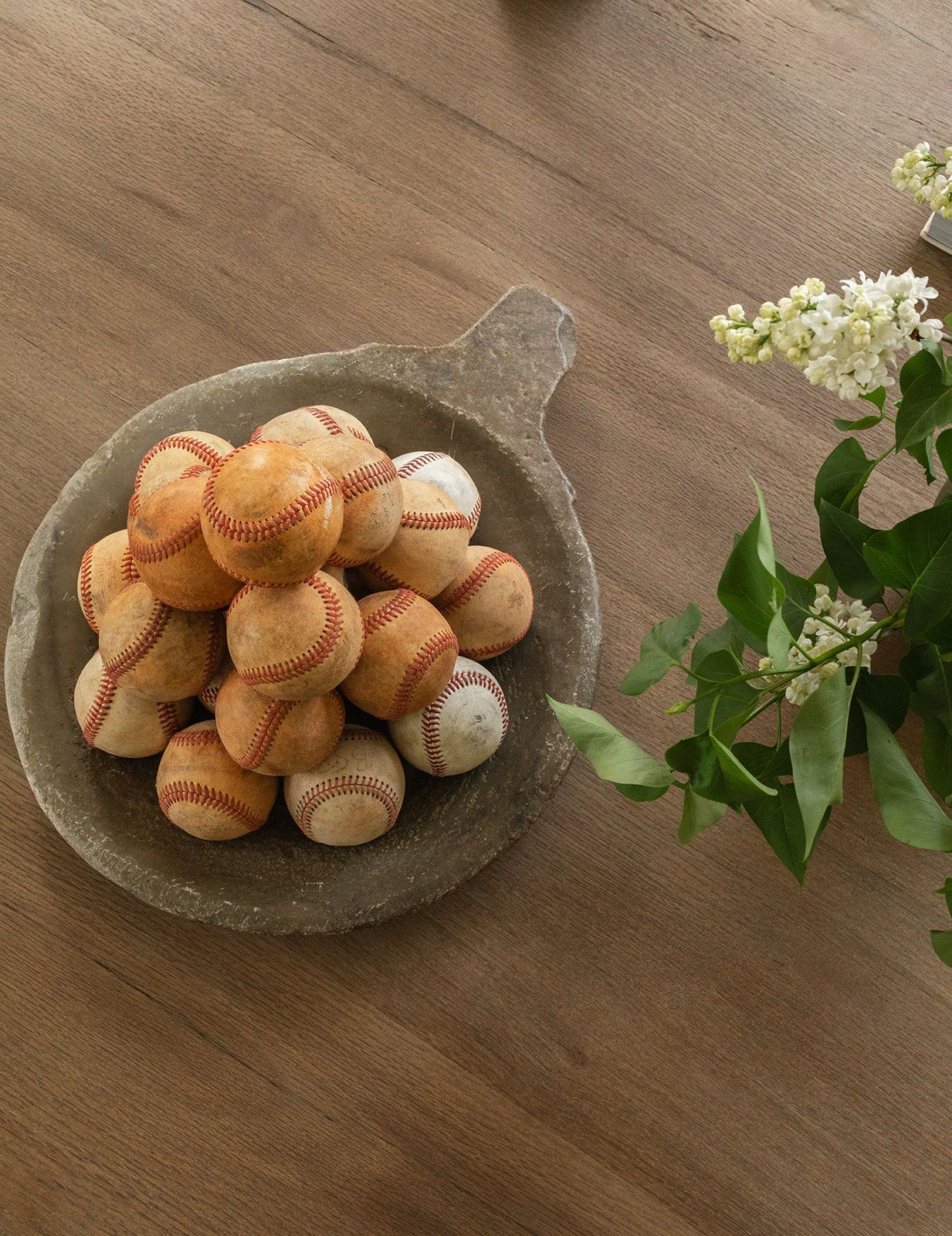 Fresh white mushrooms arranged on a rustic stone plate with green leaves on dark wooden table.